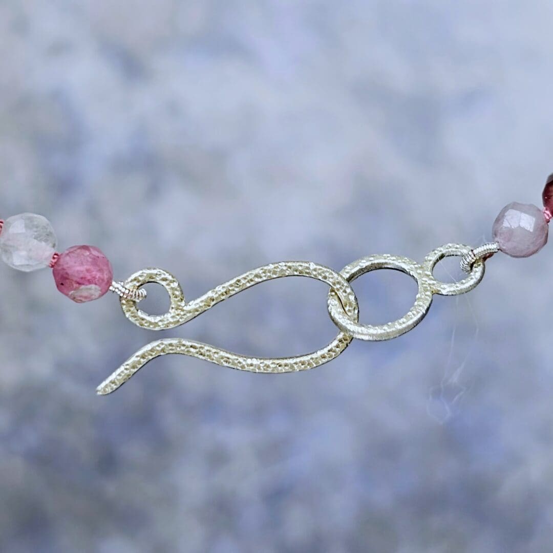 Spinel bead necklace with an etched silver flower pendant set with a small lab ruby at the centre, clasp, Isobel Kelly Jewellery