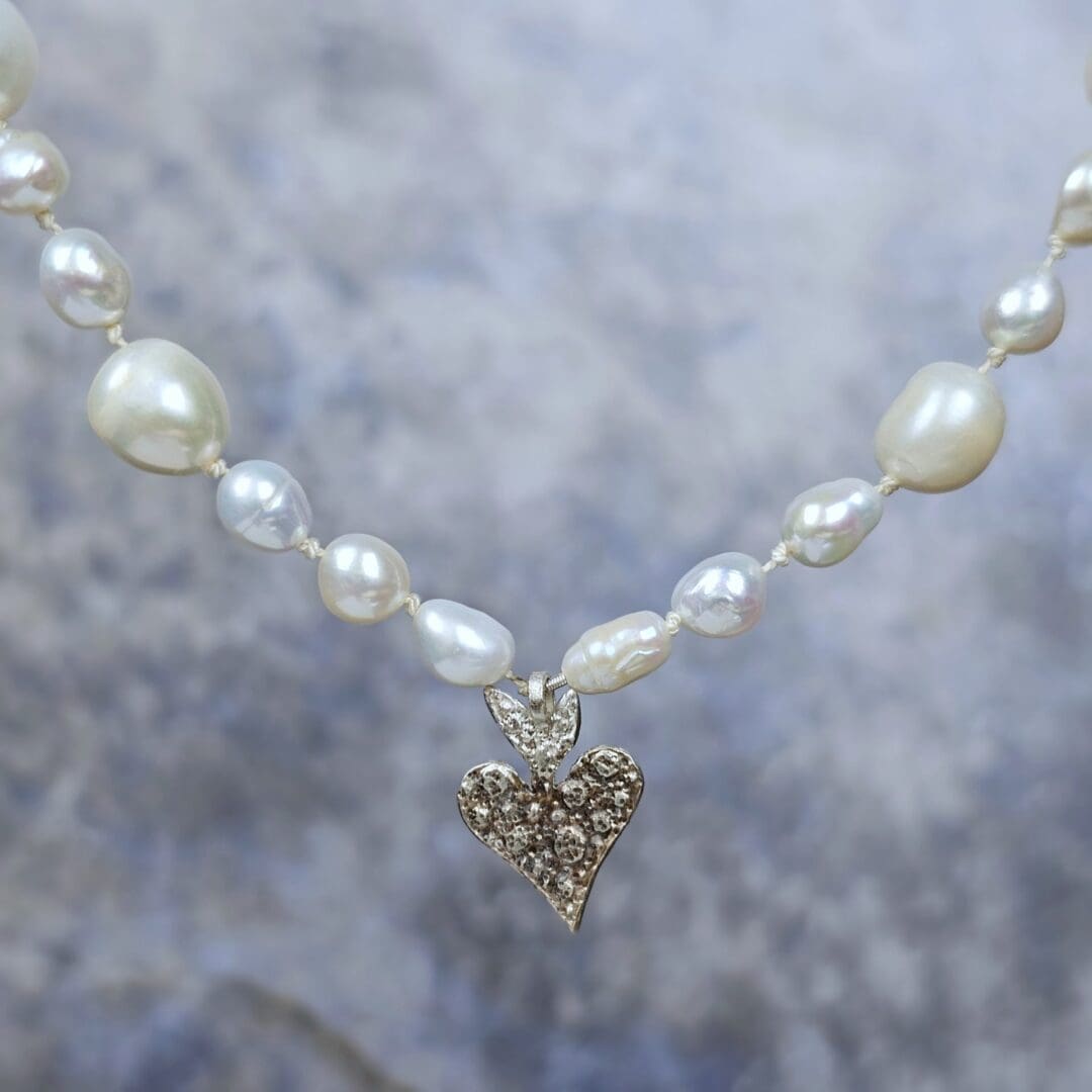 White baroque pearl necklace with a small etched silver heart pendant on a silk knotted strand, heart detail, Isobel Kelly Jewellery
