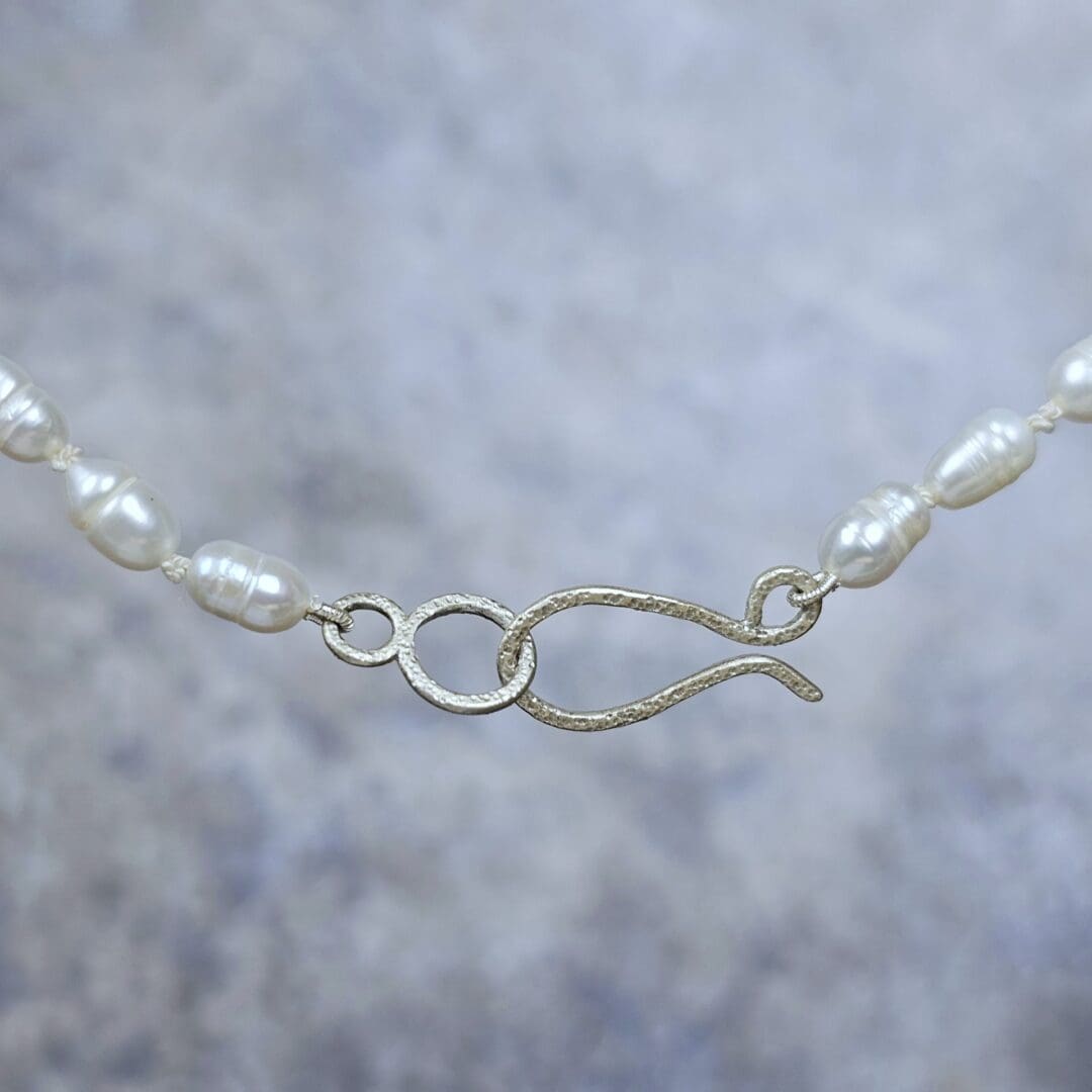 White baroque pearl necklace with a small etched silver heart pendant on a silk knotted strand, clasp, Isobel Kelly Jewellery
