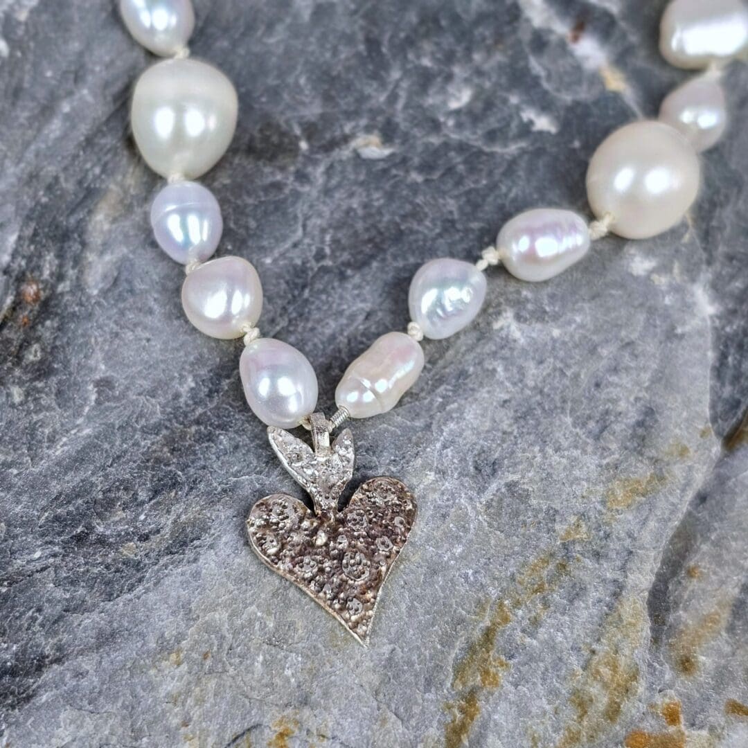 White baroque pearl necklace with a small etched silver heart pendant on a silk knotted strand, heart on rock, Isobel Kelly Jewellery