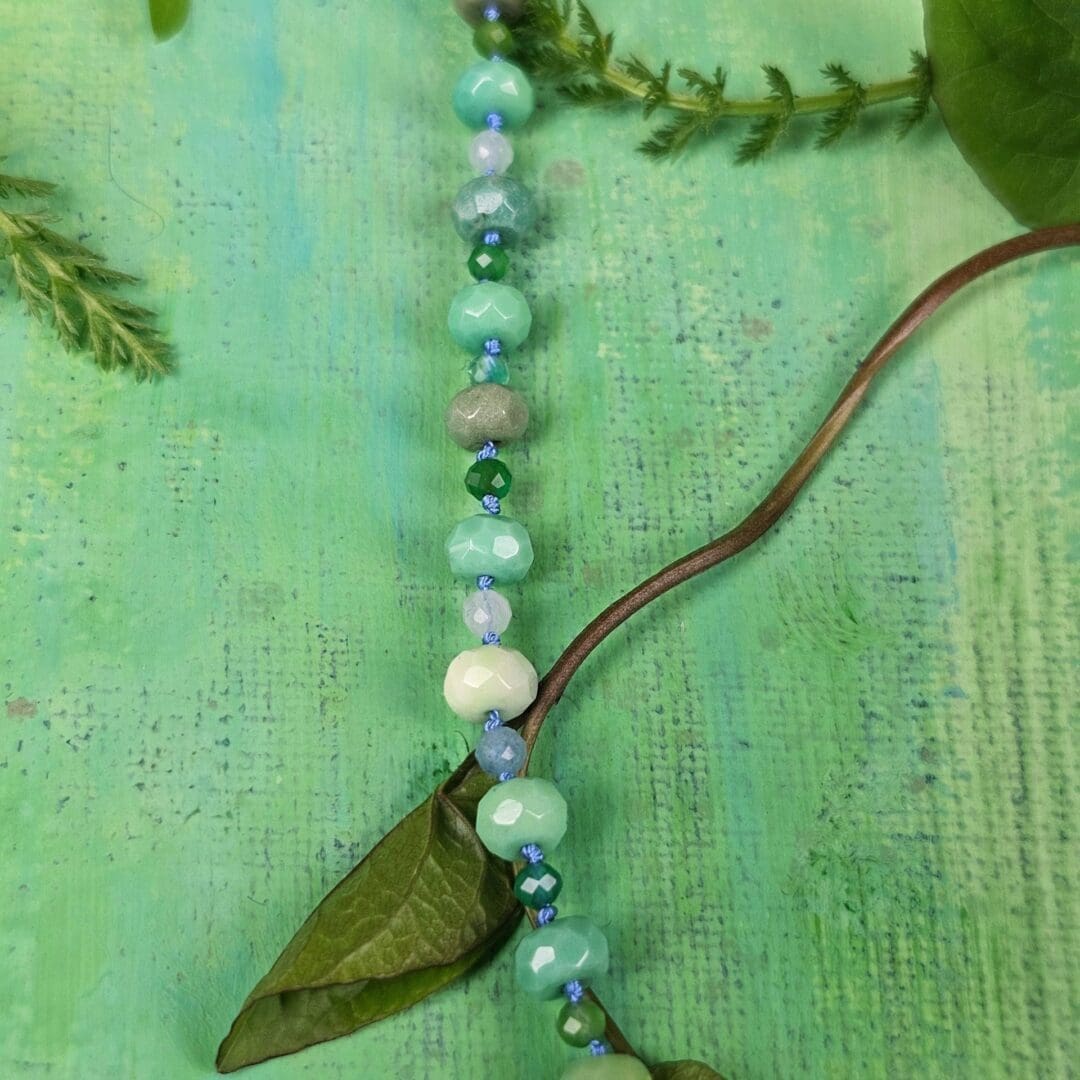 Silver leaf pendant set with lab emerald, topaz, tsavorite and spinel, bead detail green background, Isobel Kelly Jewellery