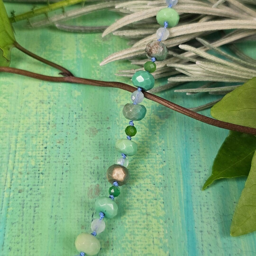 Silver leaf pendant set with lab emerald, topaz, tsavorite and spinel, bead detail green background, Isobel Kelly Jewellery