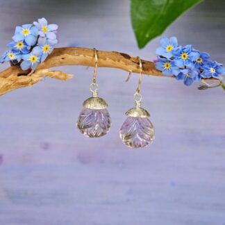 Pair of carved ametrine teardrop earrings with leaf motifs, finished with aged sterling silver and rolled gold twist hooks, hanging lilac background, Isobel Kelly Jewellery.