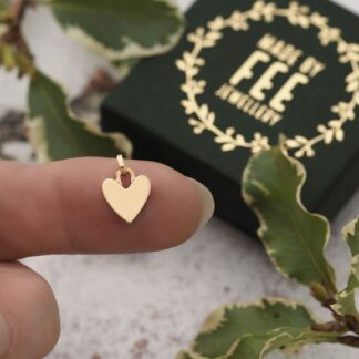 Small 9mm wide solid 9ct gold heart shown on finger for scale
