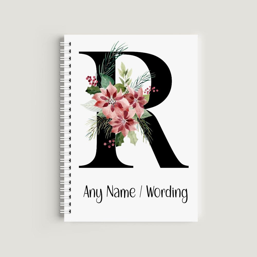A spiral-bound notebook with a white cover featuring a large, bold black letter "R" decorated with watercolor red poinsettias, green leaves, and red berries. The bottom text reads "Any Name / Wording" in a clean black font.