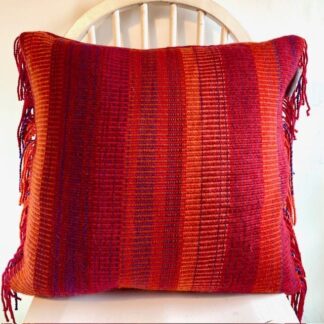 Contemporary hand woven wool cushion in a range of warm reds and oranges.