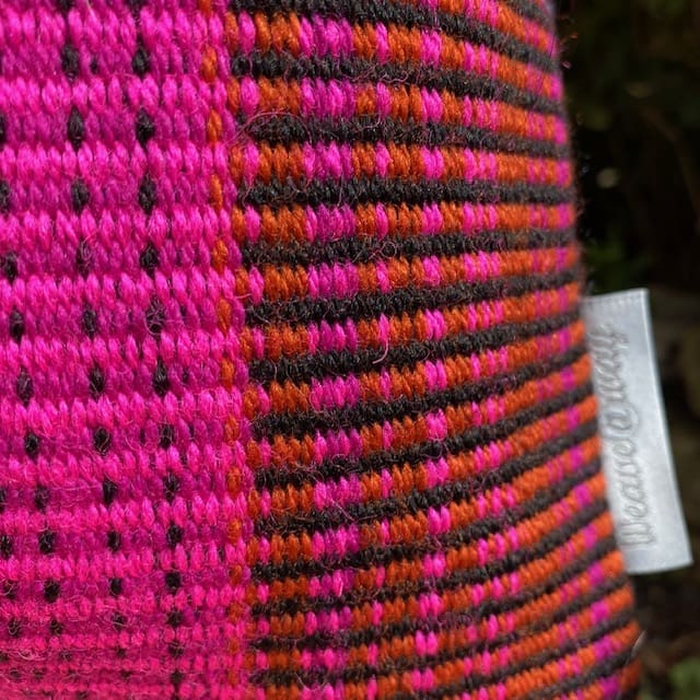 Large rectangular hand woven wool cushion ,featuring fuchsia pinks, warm reds and oranges. - Image 2