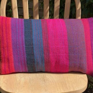 Large rectangular hand woven wool cushion ,featuring fuchsia pinks, warm reds and oranges.