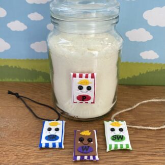 Four handmade flour jar tags resembling bags of flour. Each charm has a cute face with eyes, blushing cheeks, and a smile. The striped bags are coloured and labeled to represent the type of flour red - Plain, Blue - Self raising, Green - Strong White, Purple - Wholemeal.