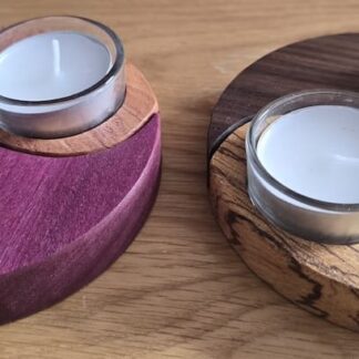 Pair of handmade yin yang wooden tea light holders in contrasting hardwoods including purpleheart, rosewood, walnut and zebrano, shown interlocked with glass candles