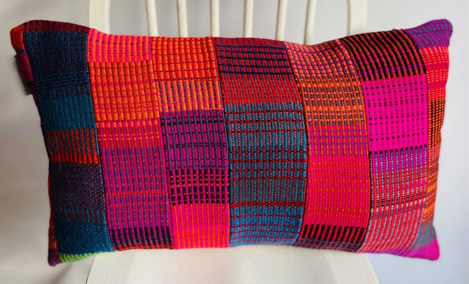 A colourful, patchwork design handwoven wool cushion