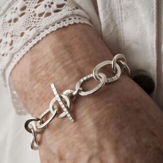 Handmade hallmarked Argentium sterling silver textured chain bracelet with chunky oval links and toggle clasp shown on wrist for scale