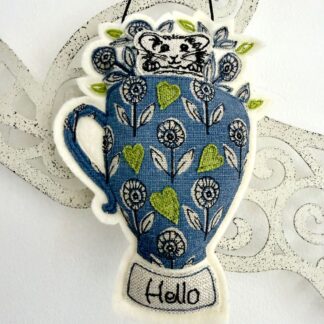 Textile wall hanging of free motion mouse in a blue floral mug with hello message, whimsical decor