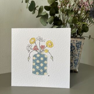 Greetings card with an appliqued fabric vase in blue and white spots with hand drawn and appliqued dainty flowers in yellow.