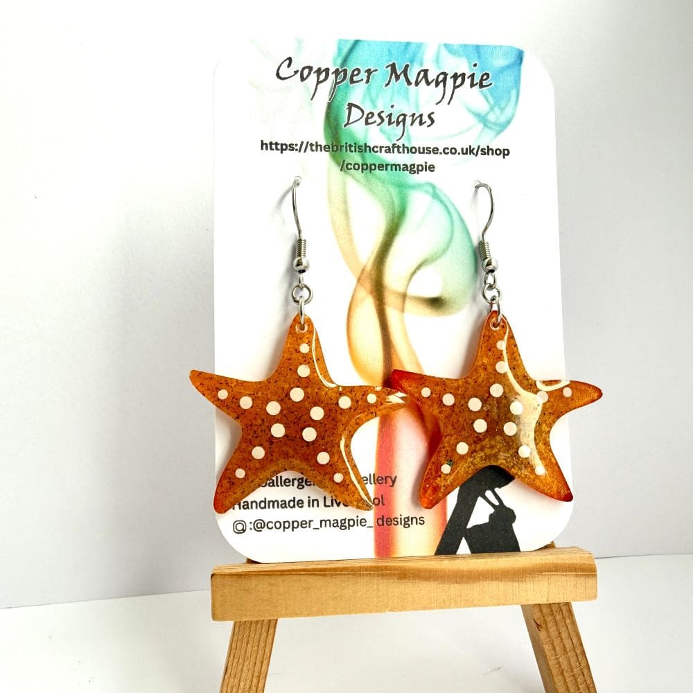 Handmade starfish resin earrings containing real Formby Beach sand by Copper Magpie Designs Liverpool, 50p to marine charities. Displayed on a branded Copper Magpie Designs card.