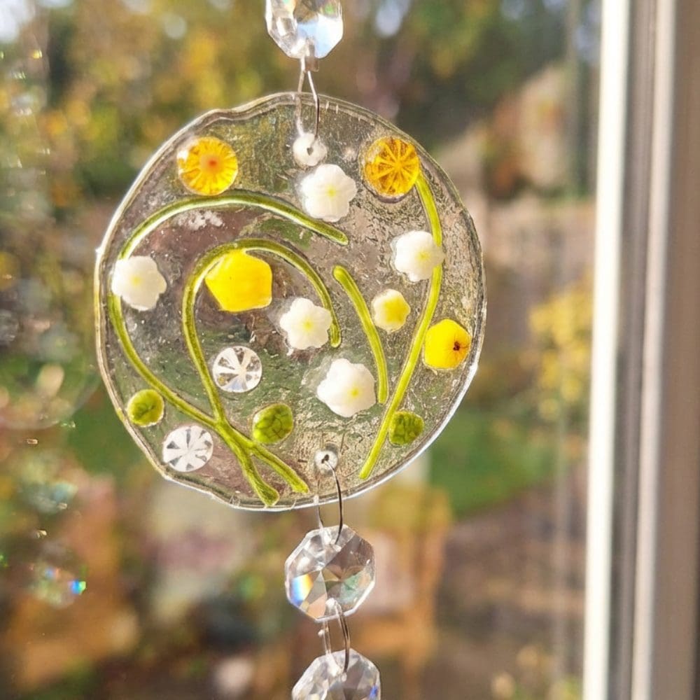 Bright sunlight shining through handmade floral glass suncatcher and crystal drops
