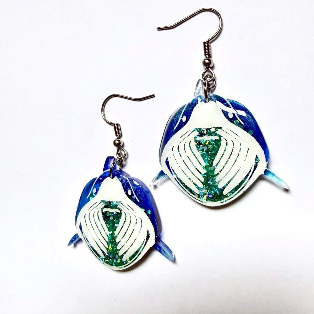 Close up of ocean blue resin and sparkling green glitter detail on handmade basking shark earrings UK