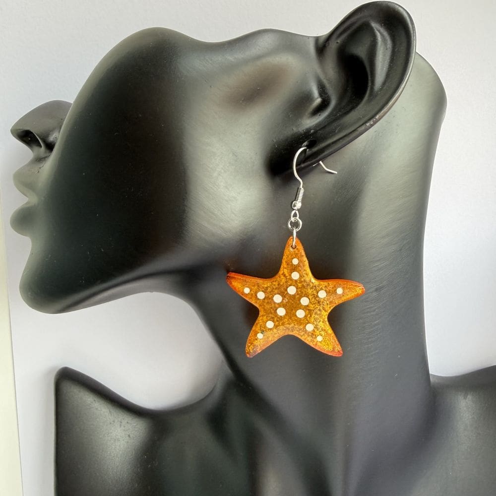 Model wearing handmade orange starfish resin earrings, coastal jewellery by Copper Magpie Designs Liverpool UK