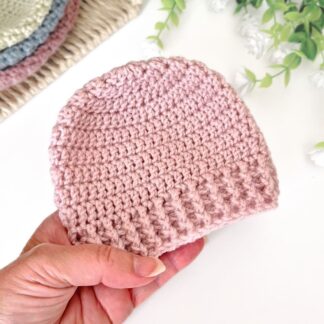 crochet baby beanie hat held in hand, shown in wild orchid