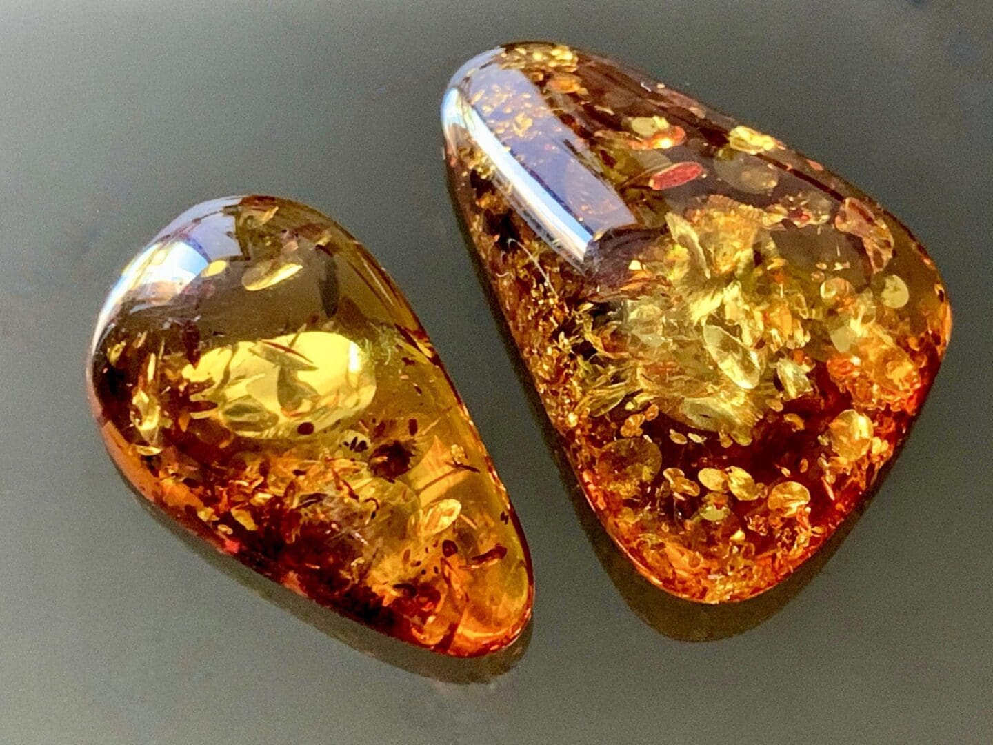 Two Baltic Amber gemstones on plain grey background