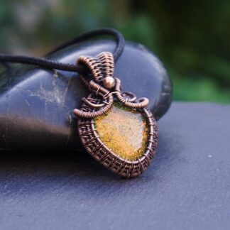 A handmade copper wire wrapped pendant featuring a golden orange dichroic glass cabochon