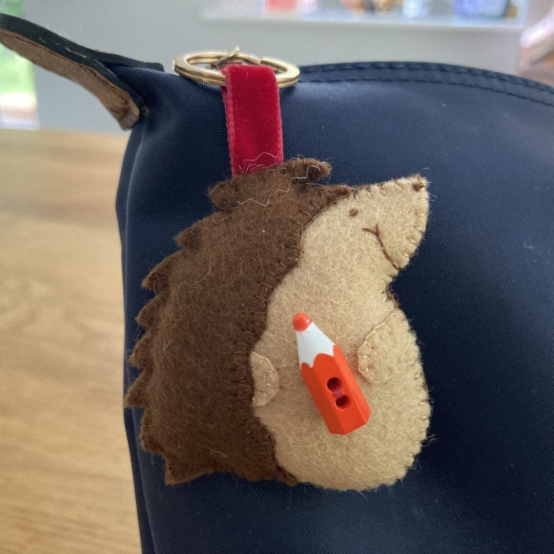 Hedgehog with a red pencil on a blue school bag