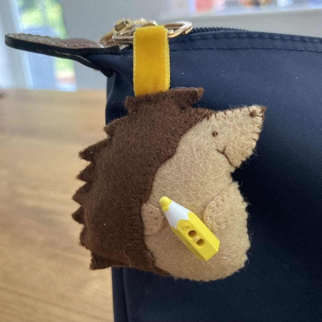 Hedgehog keyring with a yellow crayon on a blue school bag