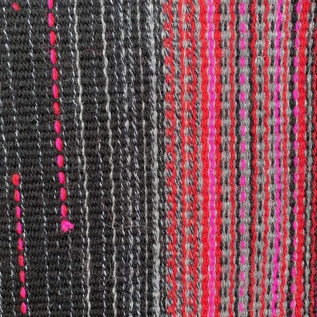 Contemporary hand woven wool cushion in a range of warm reds, soft greys and hot pinks. - Image 3