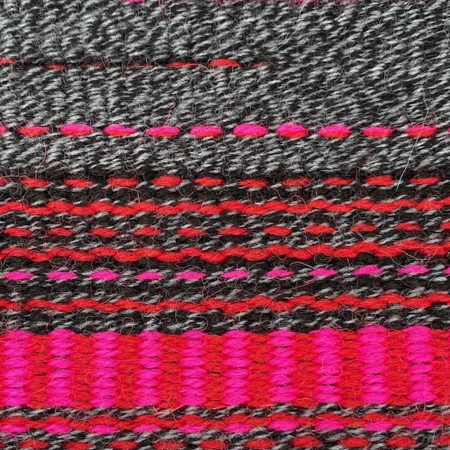 Contemporary hand woven wool cushion in a range of warm reds, soft greys and hot pinks. - Image 5