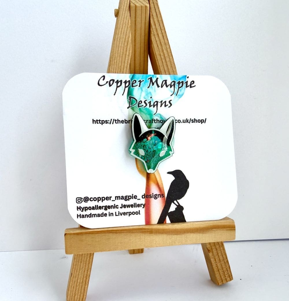 Fox/wolf pin displayed on branded Copper Magpie jewellery card sitting on an artists easel