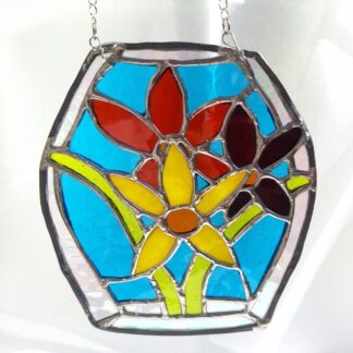 Handmade stained glass daffodil suncatcher with yellow and red flowers on a turquoise blue background