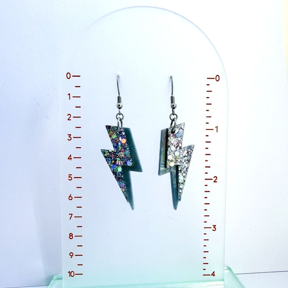 Handmade festival ready lightning bolt earrings by Copper Magpie Designs showing the size on a rulered scale.