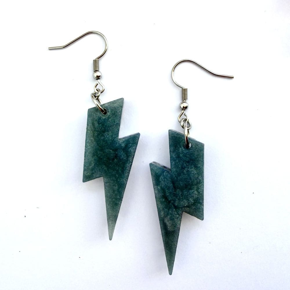 Back of handmade holographic silver lightning bolt earrings showing the smokey contrasting colour. Made using hypoallergenic surgical steel, they are suitable for sensitive ears. Displayed on a white background.