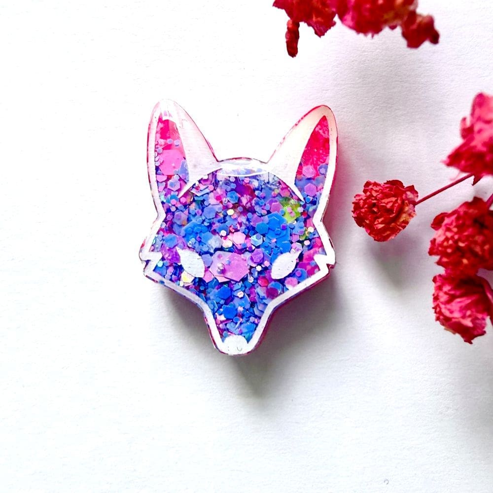 Pink holographic glitter fox resin pin badge handmade by Copper Magpie Designs Liverpool UK. Displayed on a white background with pink flowers.