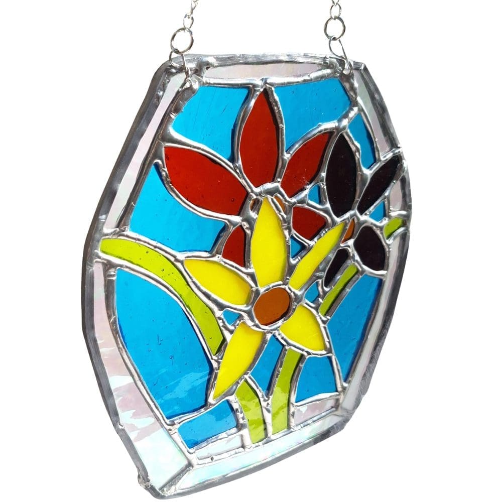 Close up of handmade stained glass floral suncatcher showing yellow daffodil and red flower detail