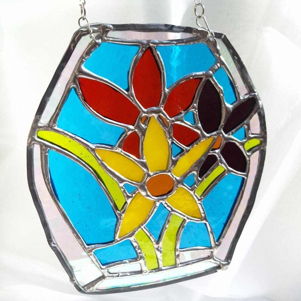 Leaded stained glass spring suncatcher hanging in a window with silver plated chain