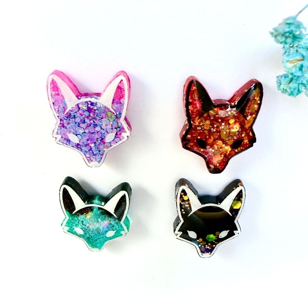 Angled shot of wildlife pins by Copper Magpie Designs showing variation in colours.
